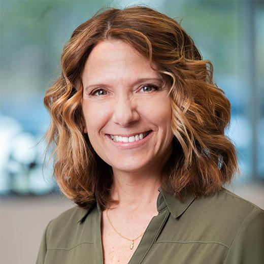 Mature woman with shoulder-length caramel brown layers and fine highlights blending scattered gray strands.